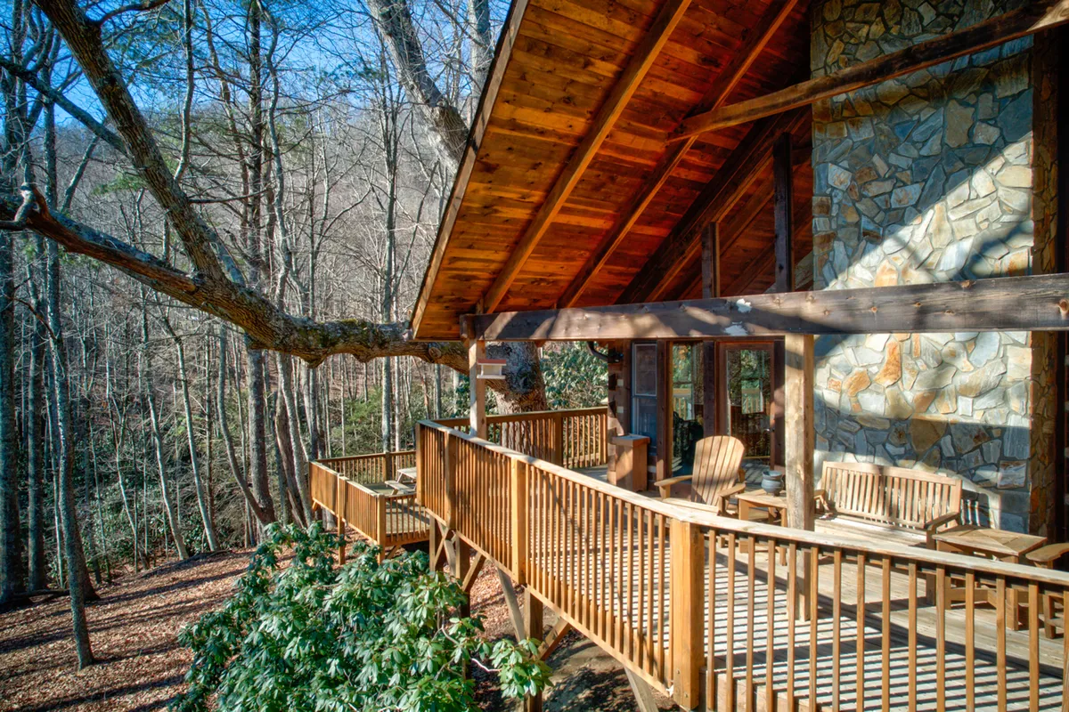 A tranquil outdoor deck with a stone wall and large tree offering a peaceful seating area. Surrounded by nature, the deck provides a cozy space to relax, read, or socialize while soaking in the mountain atmosphere. The area is ideal for observing seasonal changes and enjoying morning coffee or evening stargazing.