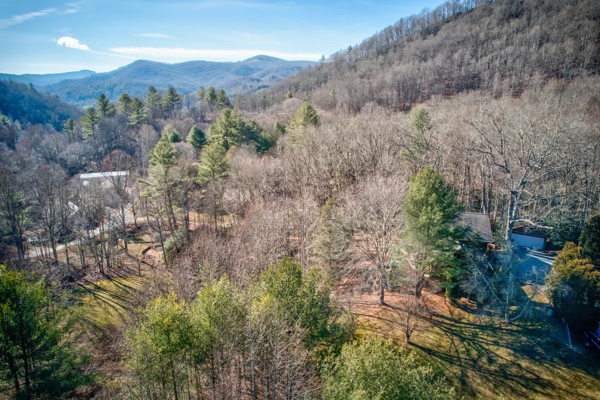 A sweeping vista of rolling hills, dense forests, and scattered residential buildings under vast skies. The view captures the broader Valle Crucis setting and the scenic natural beauty surrounding Fox's Lair.
